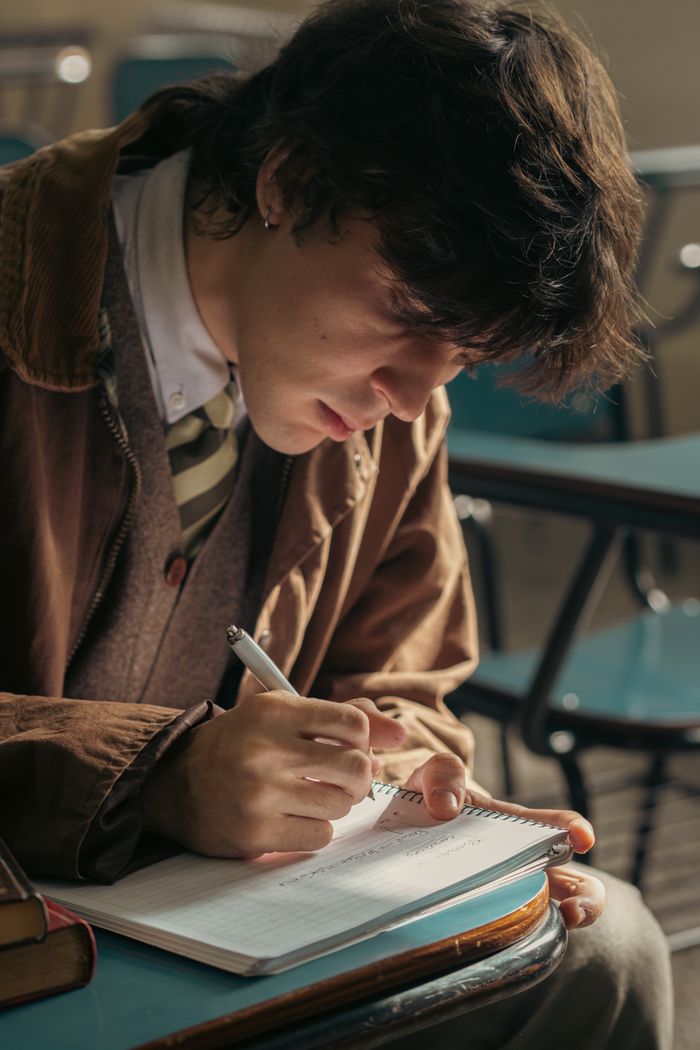 services-01 University student writing in a classroom in Buenos Aires, Argentina, with intense focus and concentration.